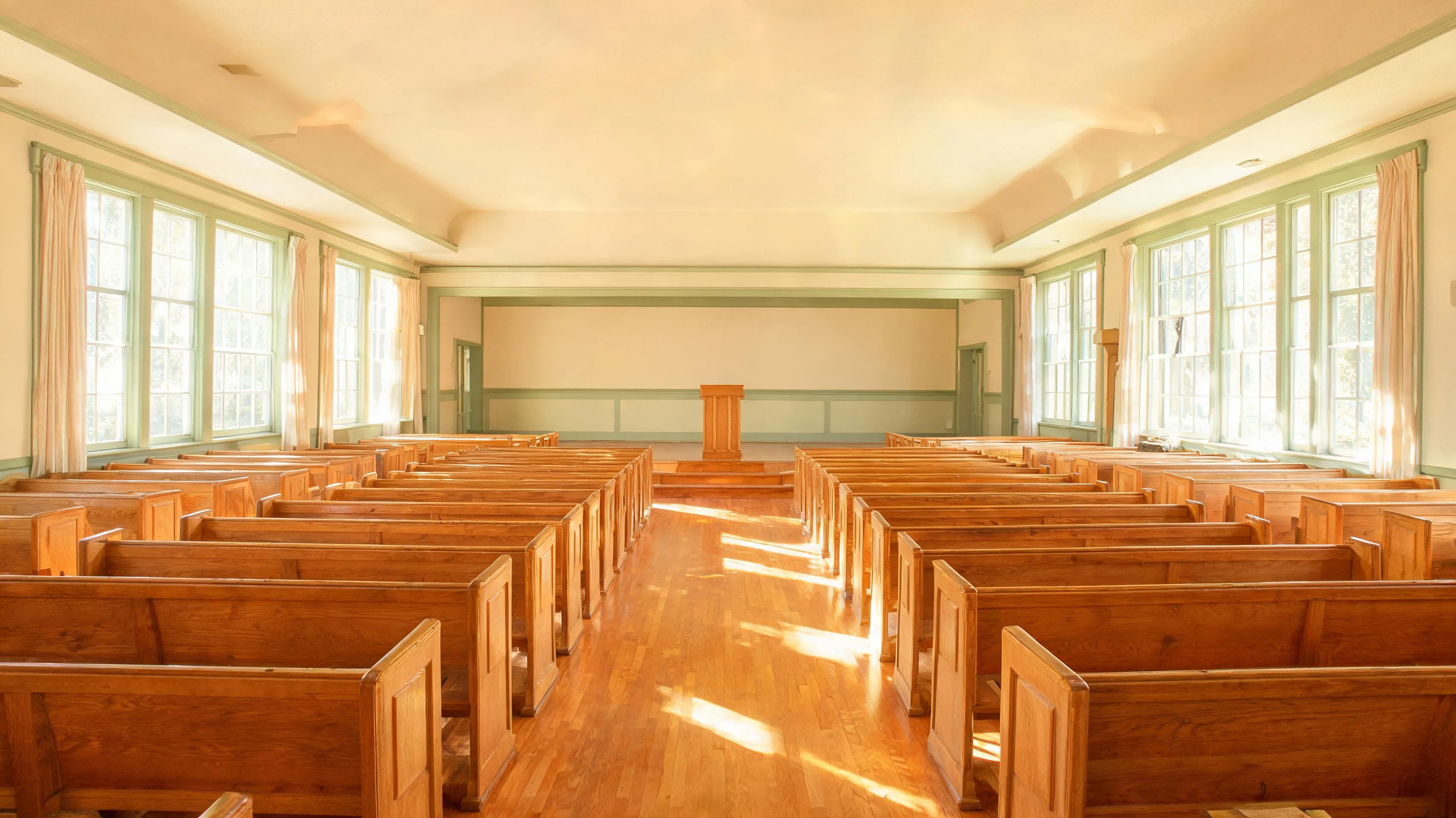 Clean church hall with polished wood floors, ordered seating and natural light